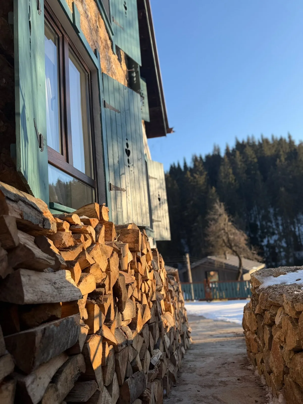 Happy House през зимата — подредени дърва и заснежени върхове